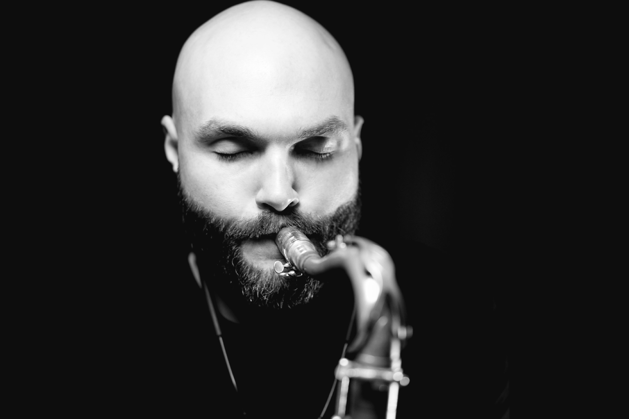 Black-and-white close portrait of a saxophone player with his eyes closed